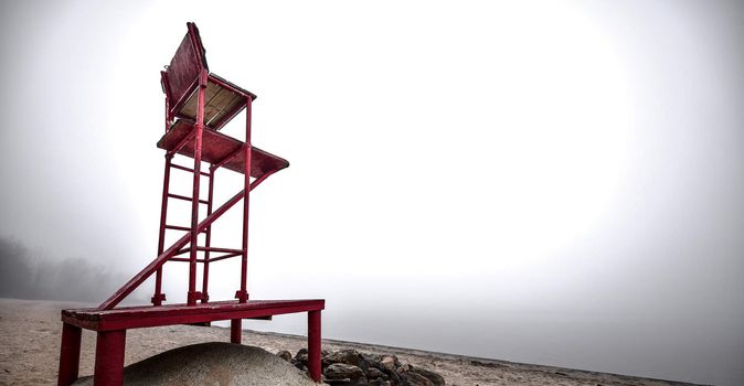 A lonely lifeguard seat stands empty in the fog on a November beach in Ontario Canada.