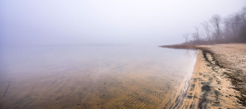 A lonely empty beach in November autumn fog in Ontario Canada.