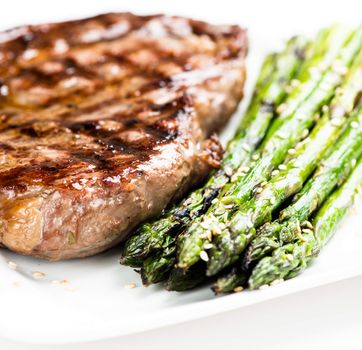 Grilled steak and asparagus on plate close up