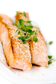 Fried salmon with sesame seeds and herbs on white plate