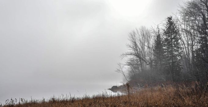 Rapidly changing thick fog envelopes the bay - obscured sunshine beaming through, bright diffusion, early sunrise Pembroke, Ontario.