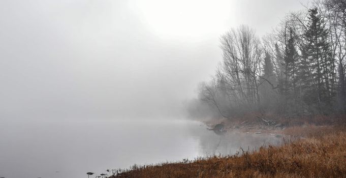 Rapidly changing thick fog envelopes the bay - obscured sunshine beaming through, bright diffusion, early sunrise Pembroke, Ontario.