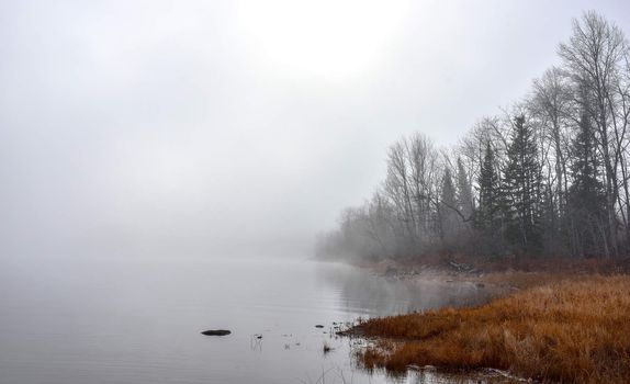 Rapidly changing thick fog envelopes the bay - obscured sunshine beaming through, bright diffusion, early sunrise Pembroke, Ontario.