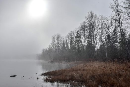 Rapidly changing thick fog envelopes the bay - obscured sunshine beaming through, bright diffusion, early sunrise Pembroke, Ontario.