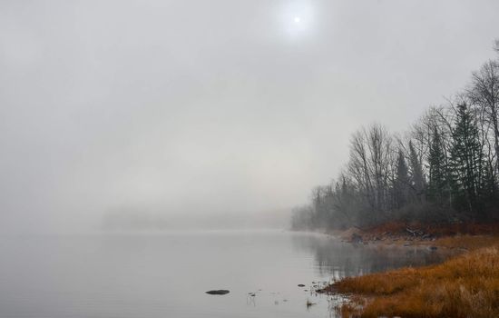 Rapidly changing thick fog envelopes the bay - obscured sunshine beaming through, bright diffusion, early sunrise Pembroke, Ontario.