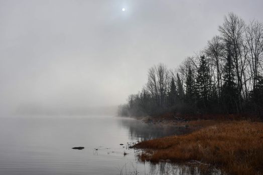 Rapidly changing thick fog envelopes the bay - obscured sunshine beaming through, bright diffusion, early sunrise Pembroke, Ontario.