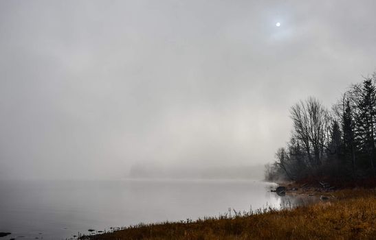 Rapidly changing thick fog envelopes the bay - obscured sunshine beaming through, bright diffusion, early sunrise Pembroke, Ontario.