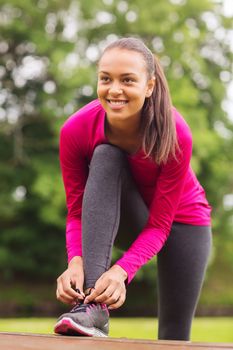 sport, exercise, park and lifestyle concept - smiling african american woman exercising outdoors