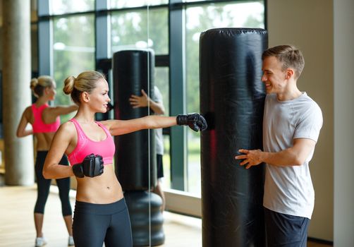 sport, fitness, lifestyle and people concept - smiling woman with personal trainer boxing in gym