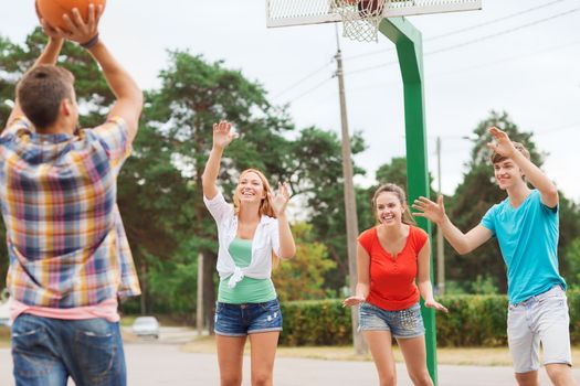 summer vacation, holidays, games and friendship concept - group of smiling teenagers playing basketball outdoors