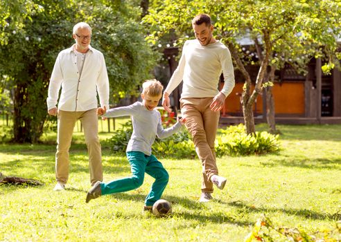 family, happiness, generation, home and people concept - happy family playing football in front of house outdoors