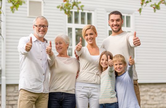 family, happiness, generation, home and people concept - happy family standing in front of house outdoors