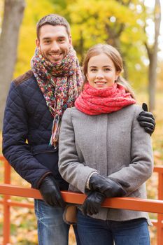 love, relationship, family, season and people concept - smiling couple hugging on bridge in autumn park