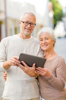 age, tourism, travel, technology and people concept - senior couple with tablet pc computer on street