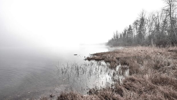 Rapidly changing thick fog envelopes the bay - obscured sunshine beaming through, bright diffusion, early sunrise Pembroke, Ontario.