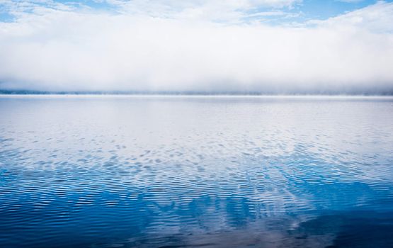 Fog rising from blue - Receding fog line on the Ottawa River - horizontal divide of two environments - air and water creates a visual spectacle.