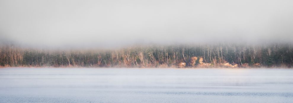 Fog rising from blue - Receding fog line on the Ottawa River - horizontal divide of two environments - air and water creates a visual spectacle.