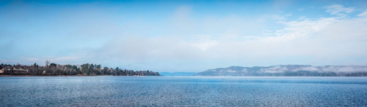 Fog rising from blue water into sky  - Panoramic fog lifting off the Ottawa River in late morning with Laurentian Hills and mountains -