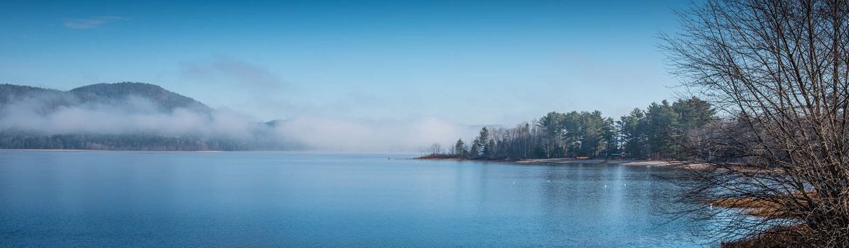 Fog rising from blue water into sky  - Panoramic fog lifting off the Ottawa River in late morning with Laurentian Hills and mountains -