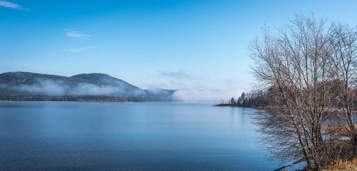 Fog rising from blue water into sky  - Panoramic fog lifting off the Ottawa River in late morning with Laurentian Hills and mountains -