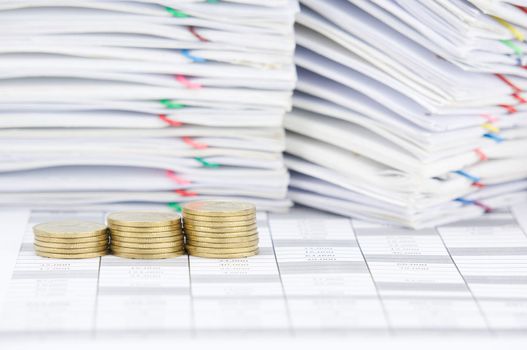 Step pile of gold coins on finance account have blur pile of paperwork as background.
