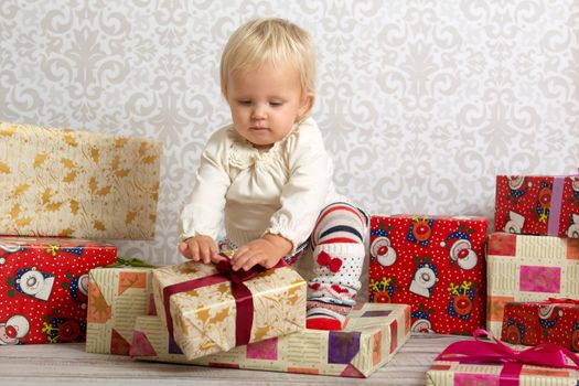 An adorable baby girl concentrate when unwrapping Christmas gift