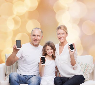 holidays, technology, advertisement and people concept - smiling family with smartphones over beige lights background