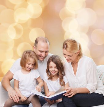 family, childhood, holidays and people - smiling mother, father and little girls reading book over beige lights background