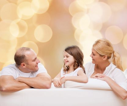 family, childhood, holidays and people - smiling mother, father and little girl over beige lights background