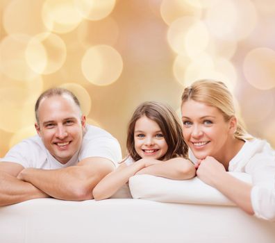 family, childhood, holidays and people - smiling mother, father and little girl over beige lights background