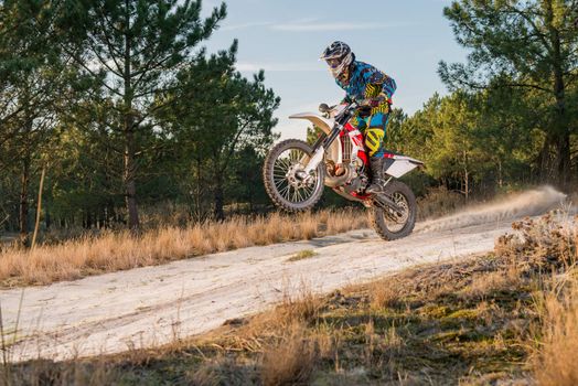 Enduro bike rider on action. Wheelie on sand terrain.