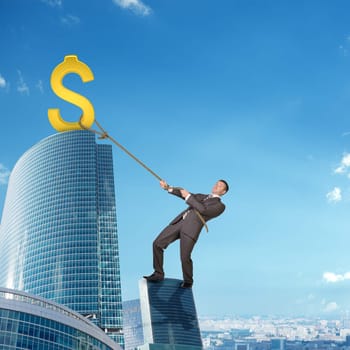 Businessman climbing skyscraper holding golden dollar sign