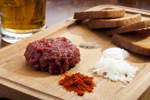 Steak tartar with the fried bread on the wooden trencher