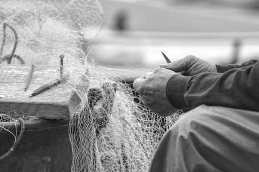 Hands of a fisherman he is cleaning his fishing net