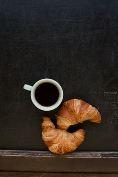 black coffee with croissant at board