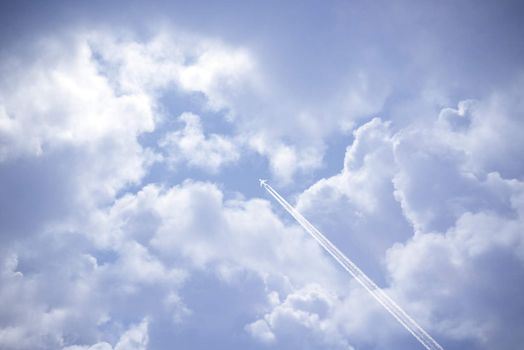 jet and its vapour trails in a cloudy blue sky