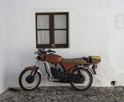 old red motor in street with white house