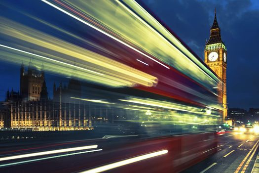 Bus crossing the bridge in front of Big Ben by night, London.