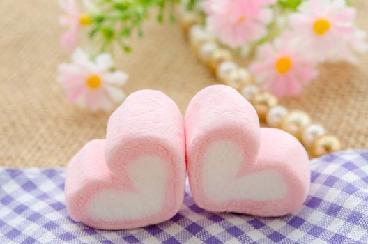 sweet heart shape of pink marshmallows with flower on tablecloth background,decoration for love and valentine day concept.