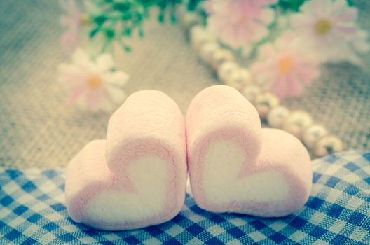 sweet heart shape of pink marshmallows with flower on tablecloth background,decoration for love and valentine day concept vintage style.
