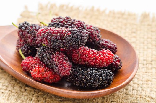 Fresh mulberry in wooden spoon on sack