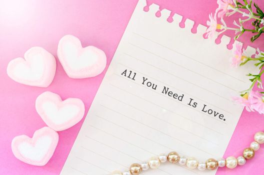 All you need is love with sweet heart shape of pink marshmallows with flower on pink background.