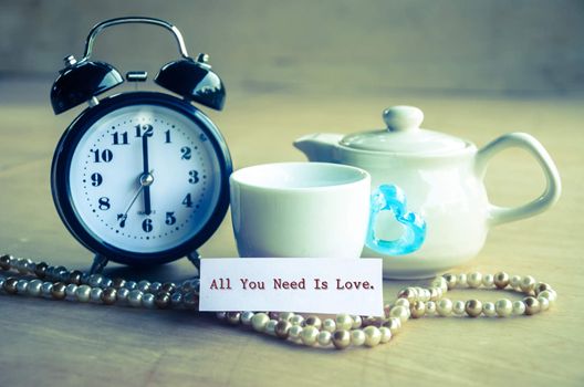 Vintage all you need is love and alarm clock with set bowl coffee on wooden background.