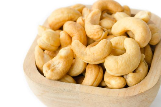 Roasted cashews nuts in wooden bowl on white background.