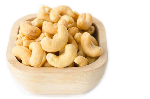 Wooden bowl with cashews on a white background.