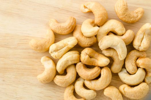 Heap of a roasted cashew nuts on wood background.