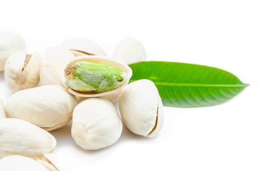 Pistachio nuts with green leaf on white background.