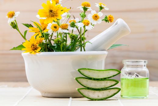 Alternative health care fresh herbal Aloe vera , oil and wild flower with mortar on wooden background.