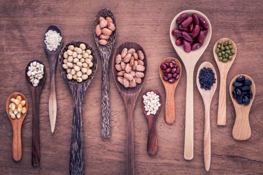 Assortment of beans and lentils in wooden spoon on teak wood background. mung bean, groundnut, soybean, red kidney bean , black bean ,sesame, corn ,red bean and brown pinto beans .