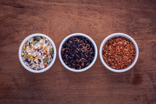 Mixed Whole grain Traditional Thai rice in the spoon and bowl best rice for healthy and clean food on teak wood background.